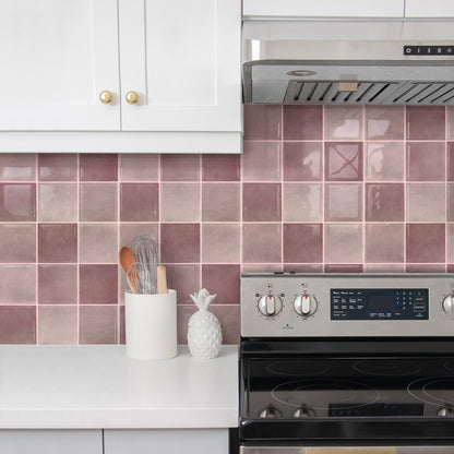 Kitchen with pink tiled backsplash, white cabinets, and stainless steel stove.