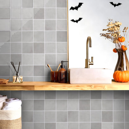 Bathroom with gray tiled walls, wooden countertop, and Halloween decorations.