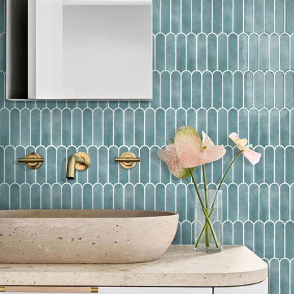 Bathroom with teal mosaic tiles, wooden sink, and pink flowers in a vase.