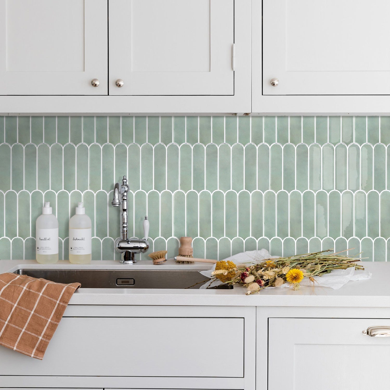 Kitchen with white cabinets, green tile backsplash, and a sink.